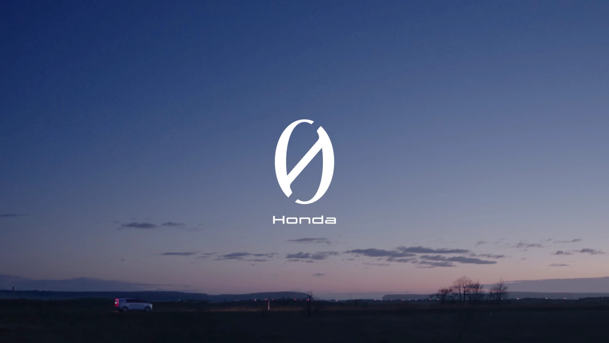 A serene dusk scene with Honda's logo and "Honda" text in white centered against a gradient sky, with a solitary white vehicle driving on a dark road below.